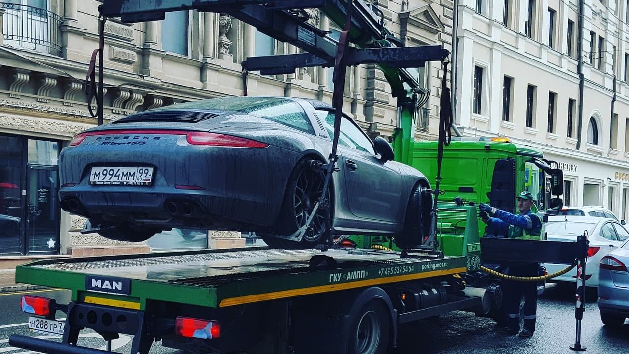 ポルシェ911がトラックの荷台にクレーンで載せられているところ